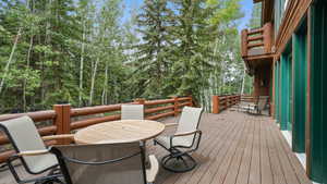 Deck with outdoor dining space and view of scattered trees