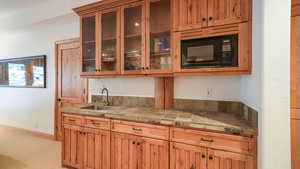 Kitchen with black microwave, glass insert cabinets, and brown cabinets
