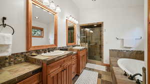 Full bath featuring a garden tub, two vanities, and a stall shower