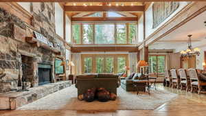 Living area with wood-type flooring, a fireplace, a chandelier, high vaulted ceiling, and a wood ceiling with exposed beams