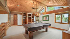 Rec room with light colored carpet, a wooden ceiling with exposed beams, billiards table, high vaulted ceiling, and a ceiling fan
