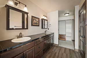 Master Full bathroom with dark wood-style floors, double vanity, and a textured ceiling