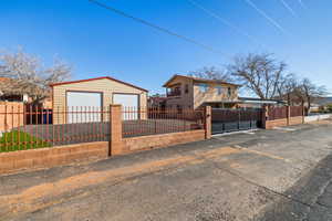 View of front of property featuring a fenced front yard, a garage, and an outdoor structure