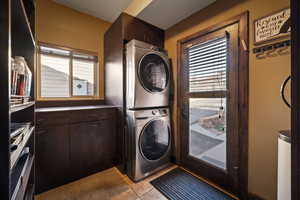 Laundry area featuring stacked washer / drying machine and light tile patterned flooring
