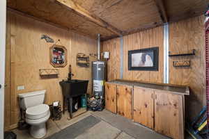 Stable Bathroom featuring wooden walls, a wooden ceiling with exposed beams, gas water heater, vanity, and tile patterned flooring