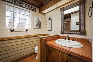Bedroom suite bathroom featuring a textured wall, a shower with door, vanity, and tile patterned flooring