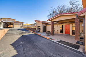 View of front facade featuring a tiled roof, stucco siding, and a patio area