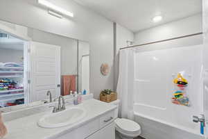 Bathroom featuring shower / bathtub combination with curtain, vanity, and a textured ceiling