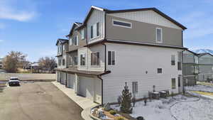 View of side of home featuring a residential view, a garage, asphalt driveway, and board and batten siding