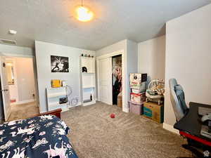 Bedroom featuring light colored carpet, a closet, and a textured ceiling