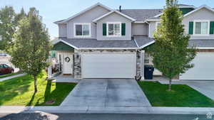 Traditional home featuring stone siding, concrete driveway, an attached garage, and stucco siding