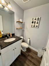 Half bath with vanity, dark wood-style floors, and a textured ceiling