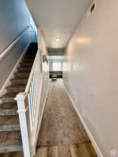 Hall featuring a textured ceiling, stairway, and light wood-type flooring