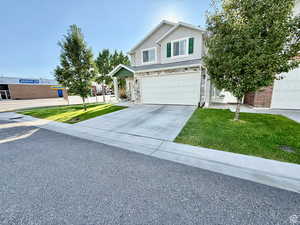 Traditional-style house featuring a front yard, driveway, a garage, and stucco siding