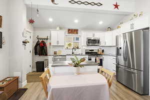 Kitchen featuring appliances with stainless steel finishes, LVP floors, Granite counters, white cabinetry, recessed lighting, and lofted ceiling