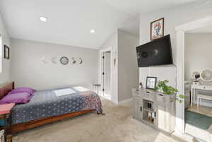 Bedroom featuring light carpet and lofted ceiling