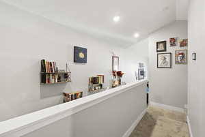 Hallway with light carpet, vaulted ceiling, and recessed lighting
