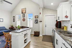 Kitchen with white cabinets, LVP floors, stainless steel dishwasher, Granite counters, backsplash, and open floor plan