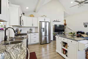 Kitchen featuring appliances with stainless steel finishes, white cabinets, open shelves, light LVP floors, and a ceiling fan