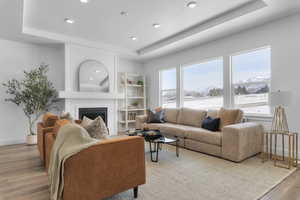 Living room with wood finished floors, a tray ceiling, a mountain view, a fireplace, and a textured ceiling