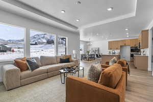 Living area with a mountain view, a textured ceiling, light wood-style floors, hanging lights, and a raised ceiling