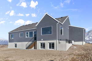 Back of property featuring a mountain view, stairs, a shingled roof, and stucco siding