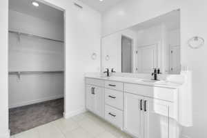 Bathroom featuring a spacious closet, double vanity, recessed lighting, light tile patterned floors, and light colored carpet