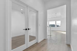 Hallway with recessed lighting, light wood-type flooring, and a raised ceiling
