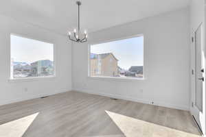 Unfurnished dining area featuring light wood-style floors and a chandelier