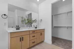 Bathroom featuring double vanity, light tile patterned flooring, a spacious closet, light colored carpet, and recessed lighting