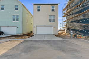 Rear view of house featuring driveway, a garage, and stucco siding