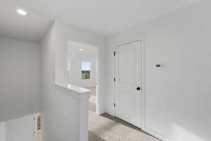 Corridor featuring an upstairs landing, carpet floors, and recessed lighting