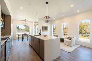 Kitchen featuring stainless steel appliances, an island with sink, hanging light fixtures, dark wood finished floors, and recessed lighting