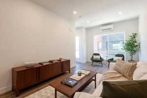 Living room featuring light wood finished floors, recessed lighting, and an AC wall unit