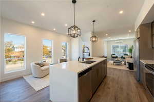 Kitchen featuring open floor plan, appliances with stainless steel finishes, dark wood-style floors, decorative light fixtures, and recessed lighting