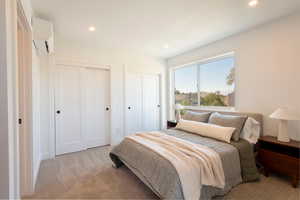 Carpeted bedroom with two closets, a wall unit AC, and recessed lighting