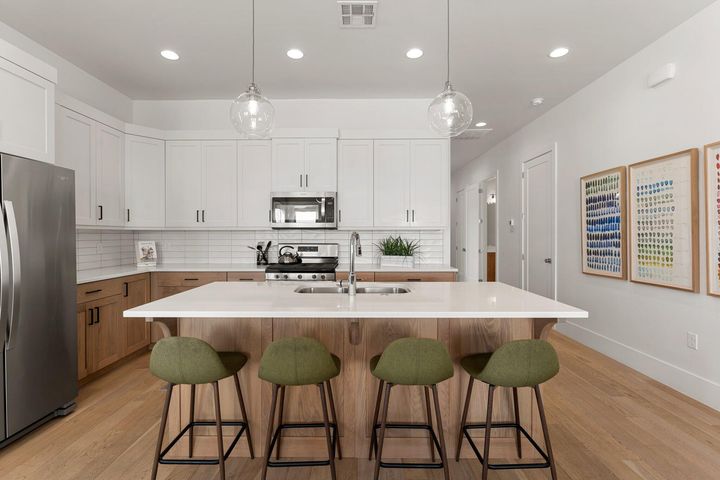 Kitchen with white cabinets, appliances with stainless steel finishes, pendant lighting, light wood-style flooring, and recessed lighting