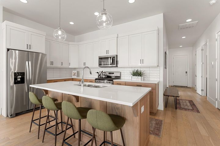 Kitchen with stainless steel appliances, white cabinets, light wood-style floors, pendant lighting, and recessed lighting