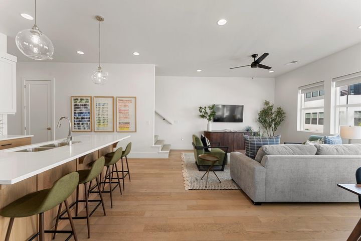 Living room with light wood-style floors, recessed lighting, stairs, and ceiling fan