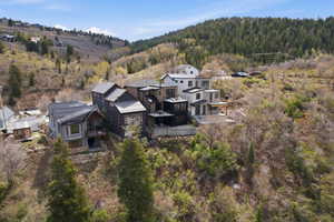 Hillside property featuring multi-level architecture, a dark metal roof, bay window, and a private balcony