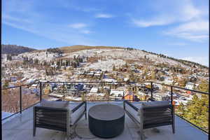 Snow covered back of property featuring a mountain view, a patio area, and a residential view