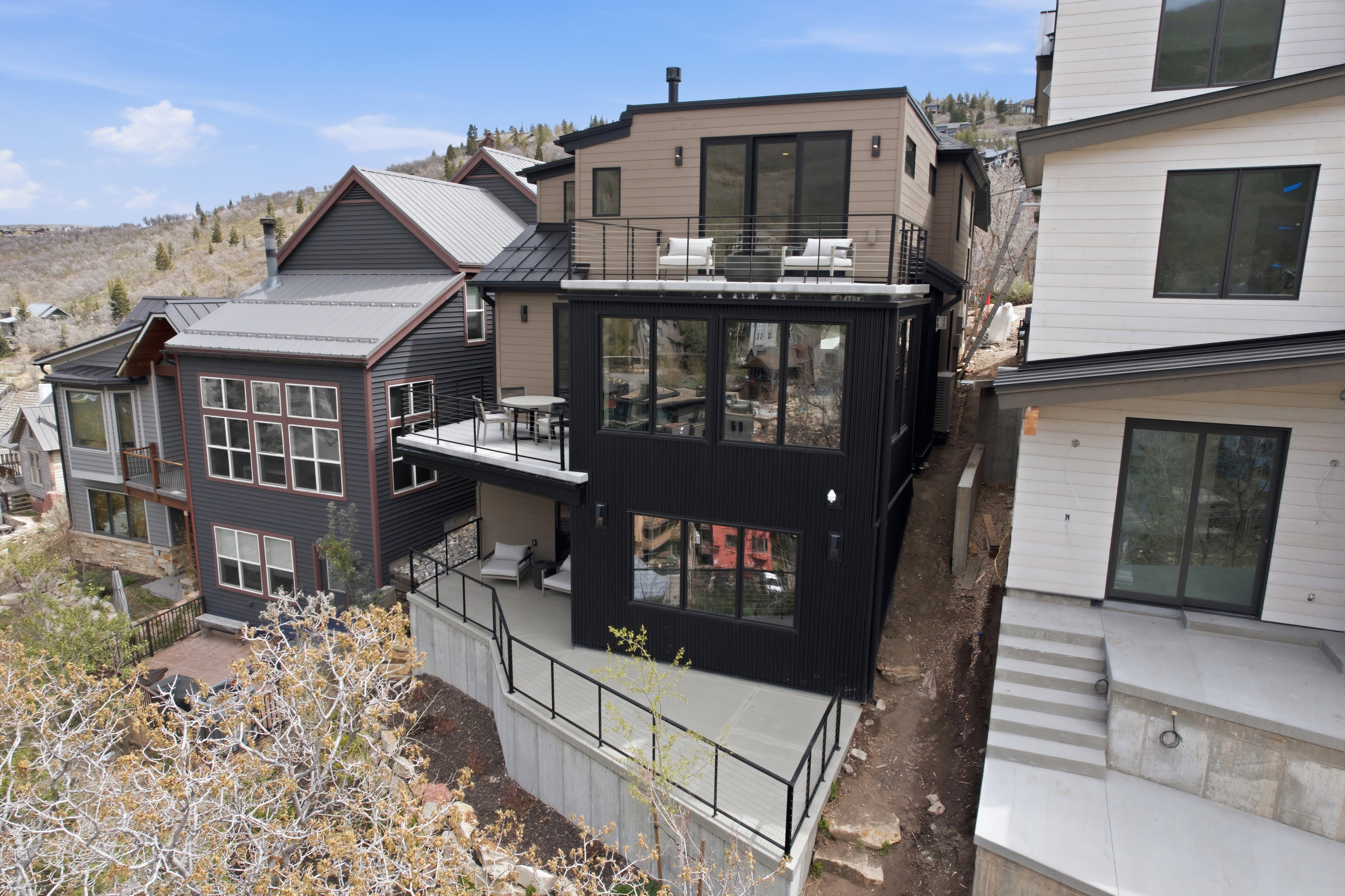 Contemporary multi-level residence featuring dark siding, multiple balconies with metal railings, extensive glazing, and a metal roof