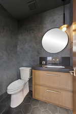 Bathroom with dark tile patterned flooring and vanity