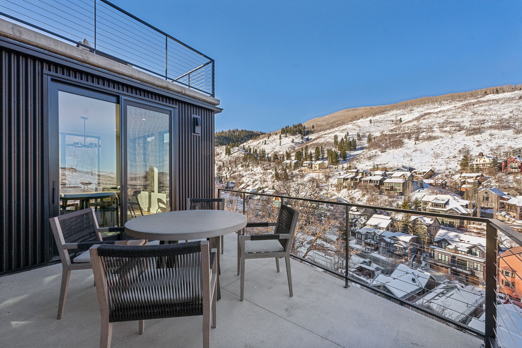 Snow covered back of property featuring a mountain view, outdoor dining space, and a patio