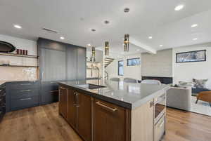 Kitchen with open shelves, hanging light fixtures, open floor plan, a center island with sink, and recessed lighting
