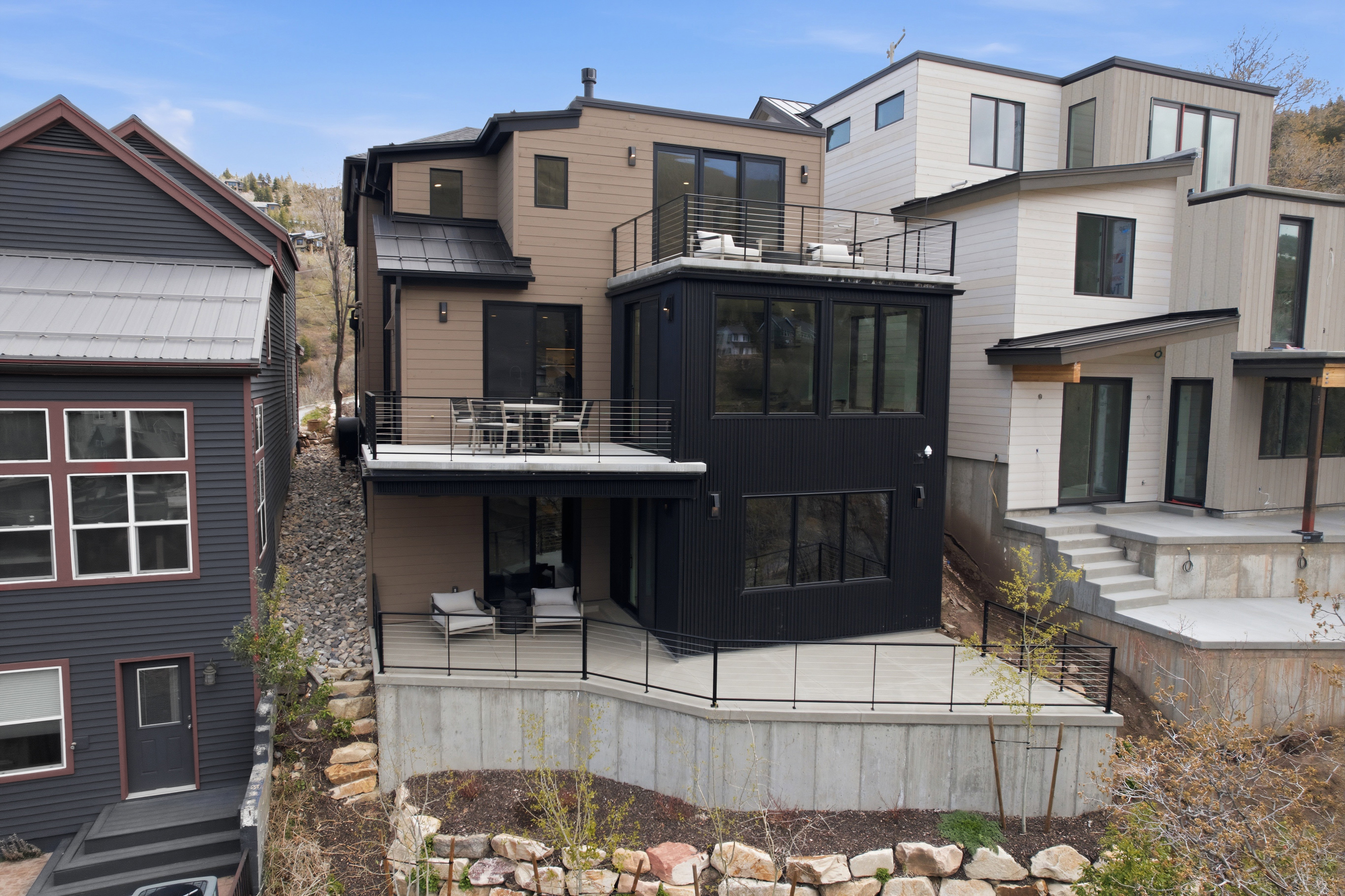 Multi-level modern residence featuring a tan and black exterior with abundant windows