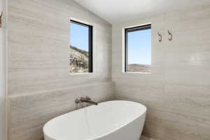 Full bathroom featuring a freestanding tub and vaulted ceiling