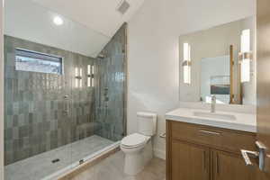 Full bath with vaulted ceiling, vanity, a stall shower, and light tile patterned floors