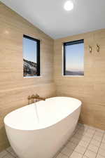 Full bath with plenty of natural light, a freestanding tub, and tile patterned flooring