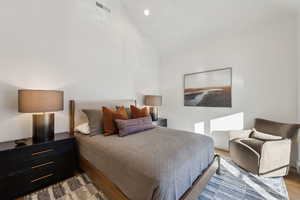 Bedroom with wood finished floors, recessed lighting, and high vaulted ceiling